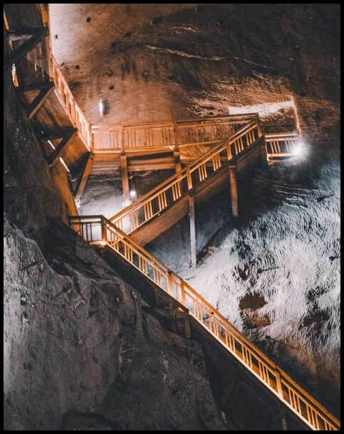 Well lit mining site with long ladders underground - D.A.C Mining Services